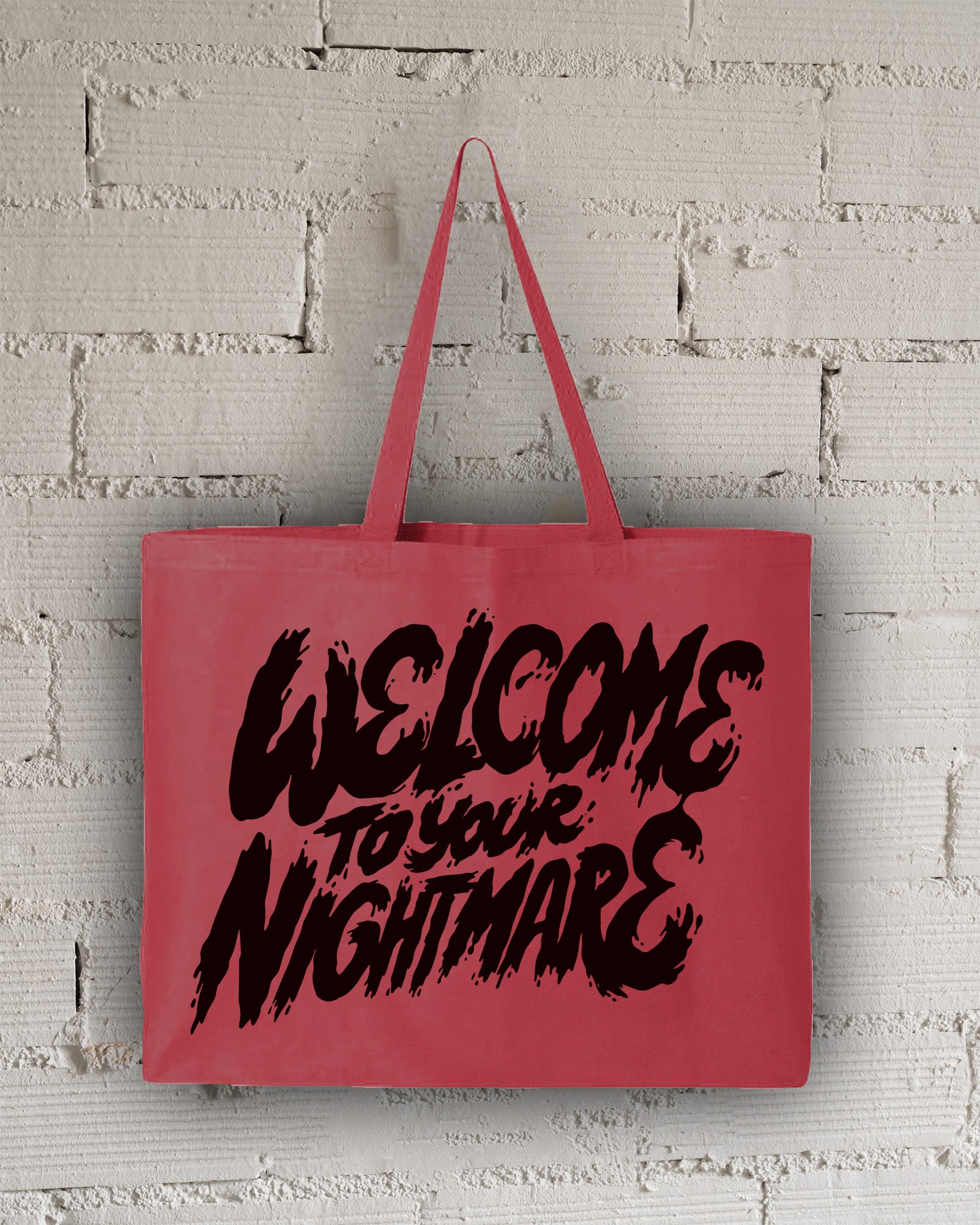 Red tote bag featuring black text that reads Welcome to Your Nightmare in a horror-style font.