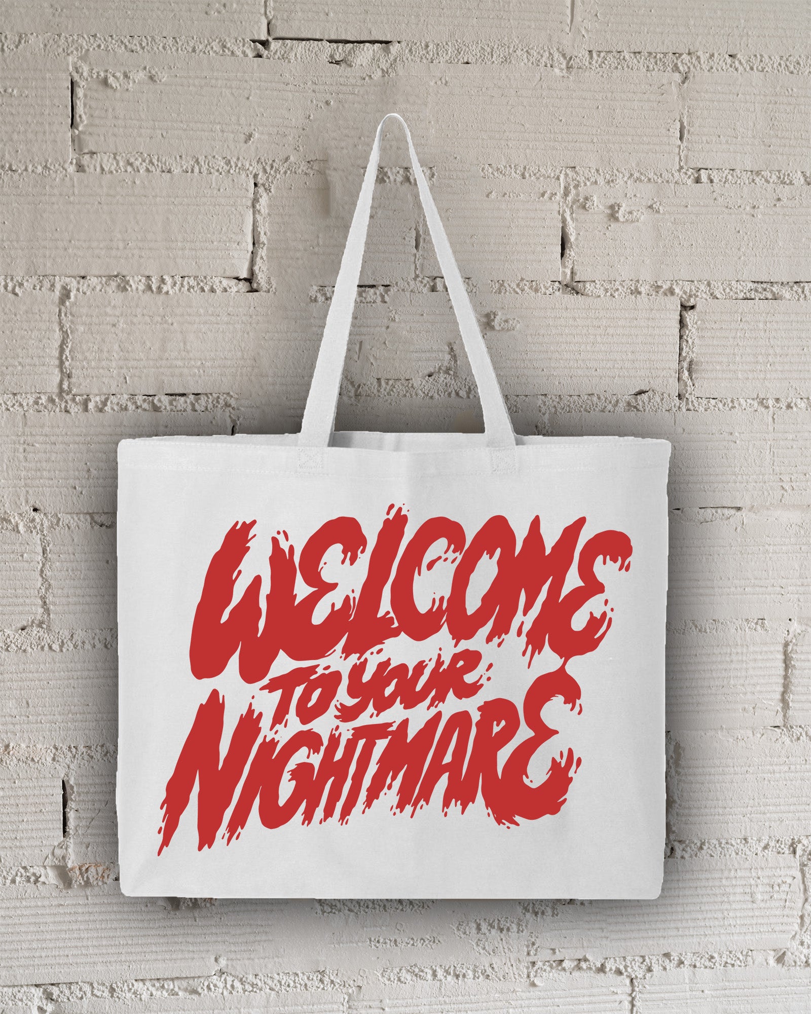 White tote bag featuring red text that reads Welcome to Your Nightmare in a horror-style font.