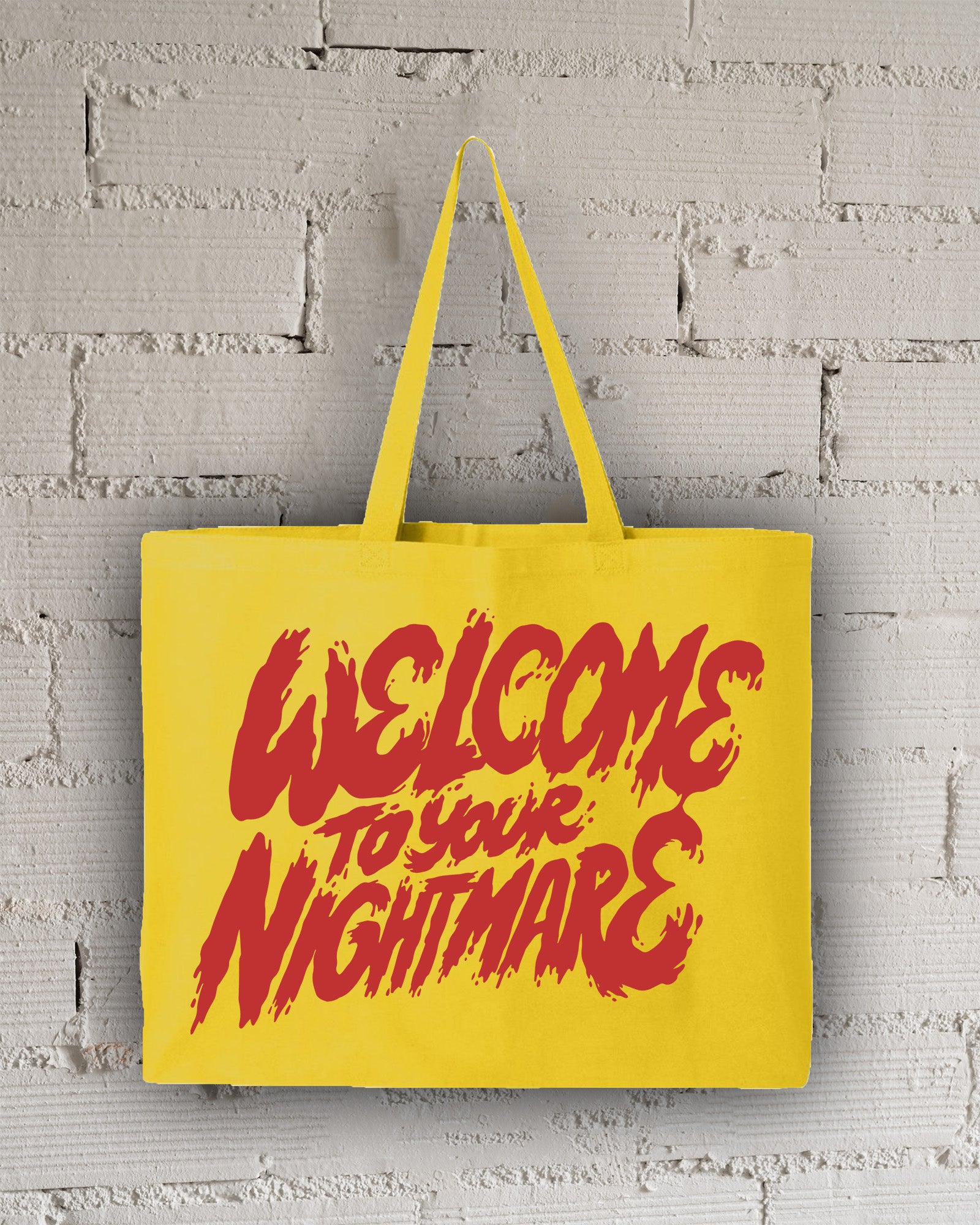Yellow tote bag featuring red text that reads Welcome to Your Nightmare in a horror-style font.