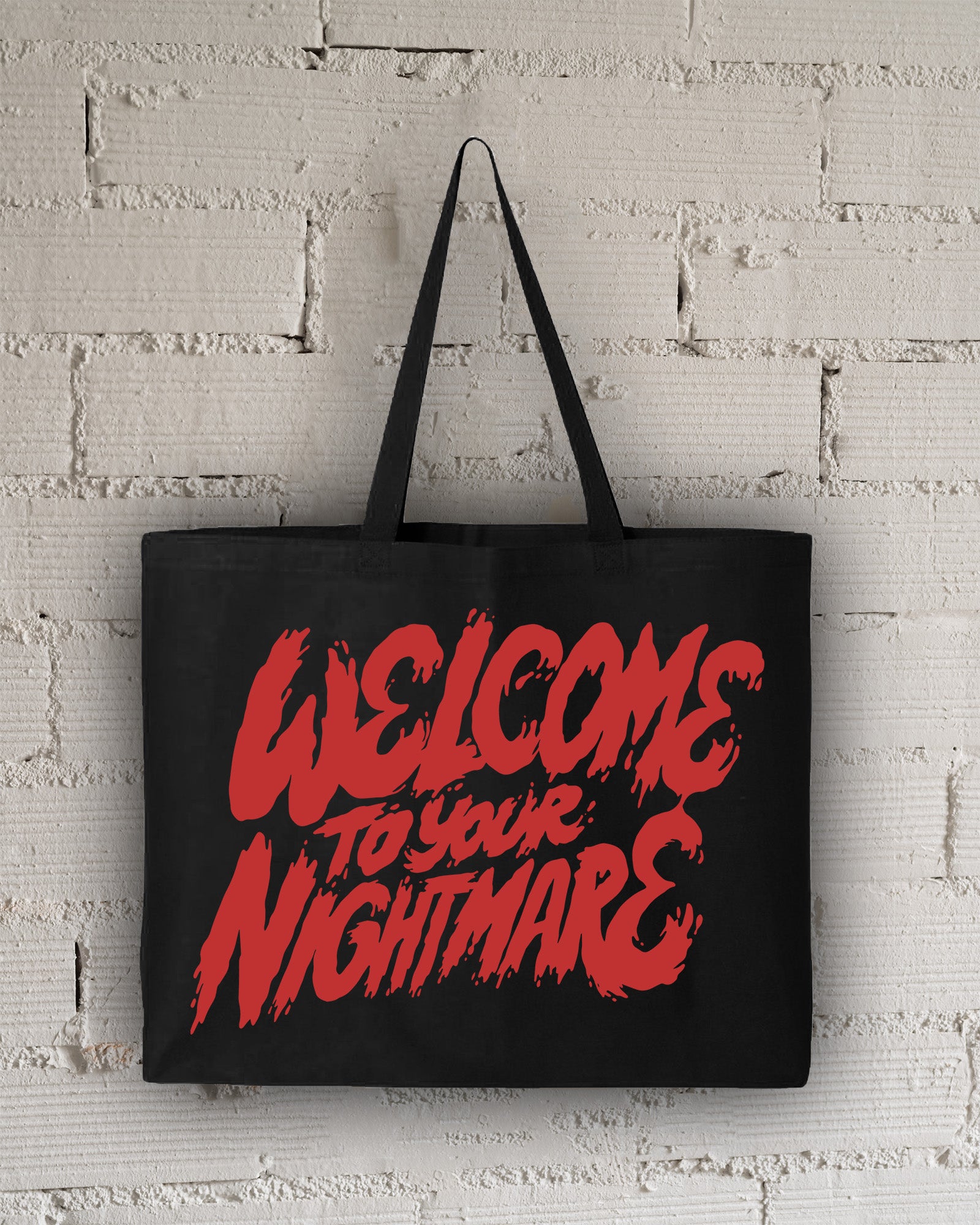 Black tote bag featuring red text that reads Welcome to Your Nightmare in a horror-style font.