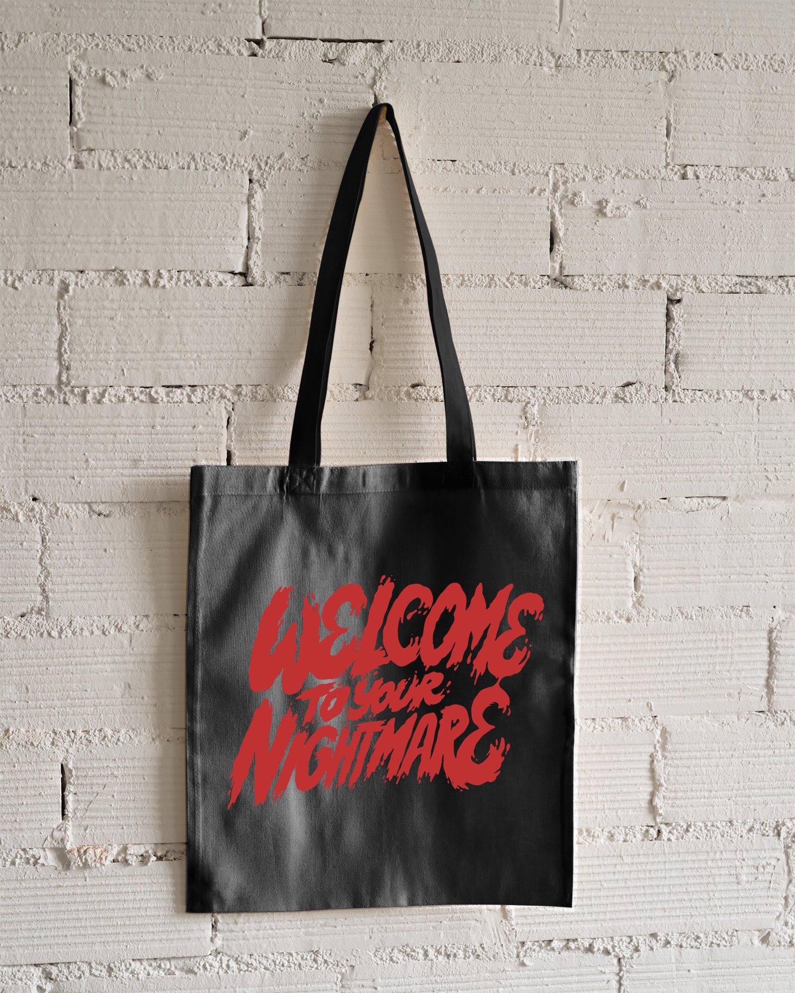 Black tote bag featuring red text that reads Welcome to Your Nightmare in a horror-style font.