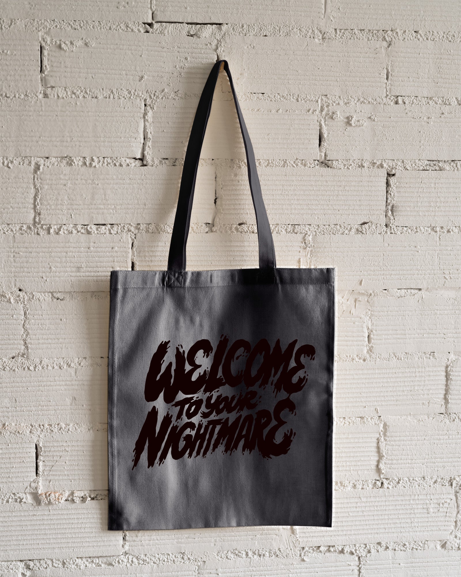 Charcoal tote bag featuring black text that reads Welcome to Your Nightmare in a horror-style font.